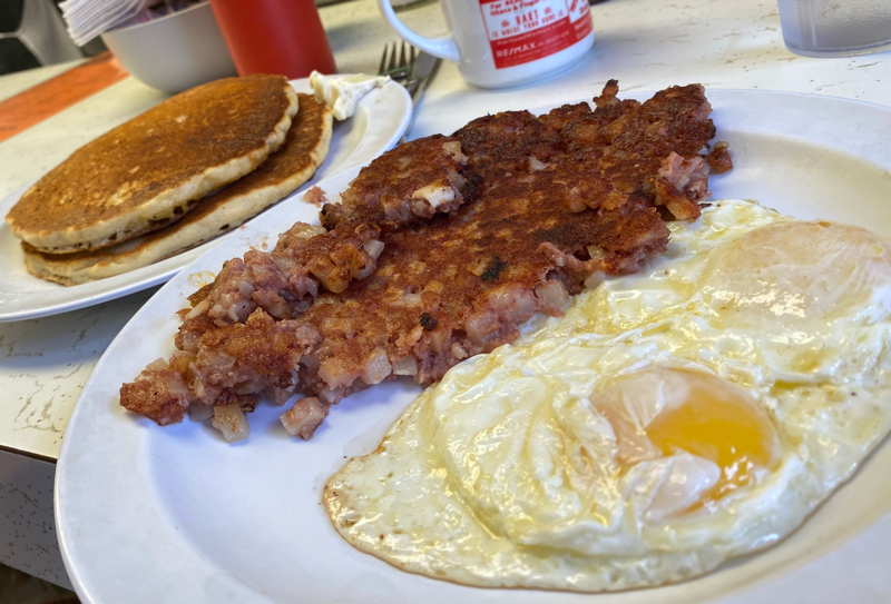 Corned beef hash, eggs, and pancakes on a diner counter